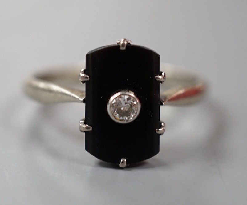 A 9ct white metal, black onyx and single stone diamond set tablet ring, size O, gross weight 2.1 grams.